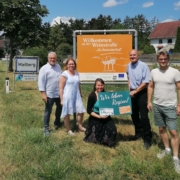 Fünf Personen präsentieren gemeinsam die neue Gebietstafel „Willkommen an der Weinstraße Weinviertel" im Rahmen des Projekts Regionsbewusstsein Weinviertel