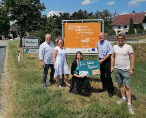 Fünf Personen präsentieren gemeinsam die neue Gebietstafel „Willkommen an der Weinstraße Weinviertel" im Rahmen des Projekts Regionsbewusstsein Weinviertel